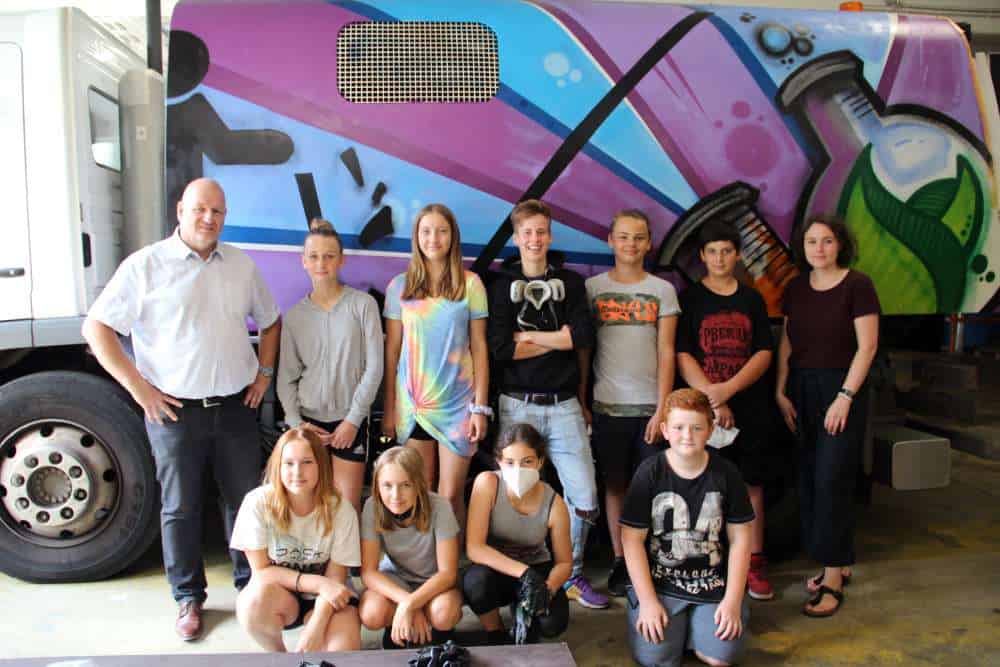 Die Teilnehmer des Graffiti-Workshops mit einer gestalteten Kehrmaschine; Quelle: vhs Völklingen